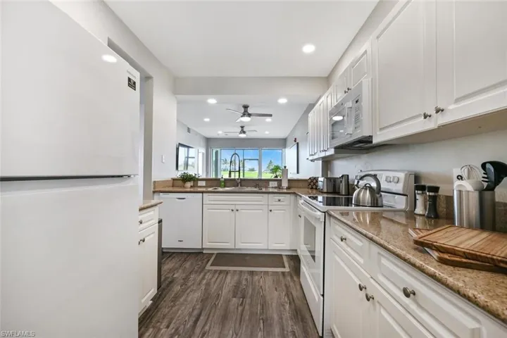 Kitchen featuring sink, white cabinets, dark hardwood / wood-style floors, and white appliances