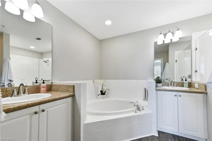 Bathroom with vanity, shower with separate bathtub, and wood-type flooring