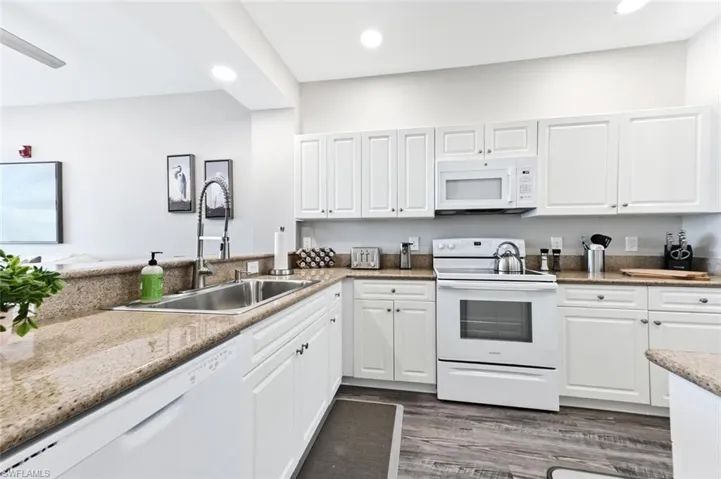 Kitchen featuring dark hardwood / wood-style floors, white cabinets, sink, and white appliances
