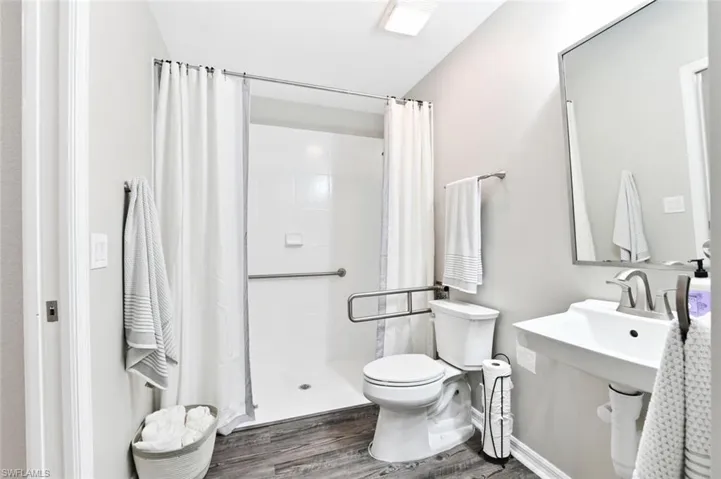 Bathroom with toilet, hardwood / wood-style floors, and curtained shower