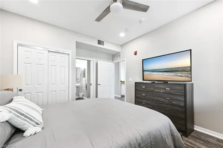 Bedroom featuring dark wood-type flooring, ensuite bathroom, a closet, and ceiling fan