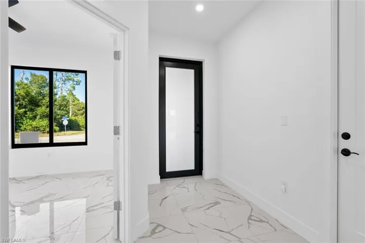 Doorway featuring baseboards, marble finish floor, and recessed lighting