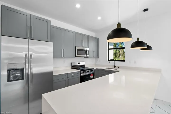 Kitchen with a sink, stainless steel appliances, light countertops, a peninsula, and recessed lighting