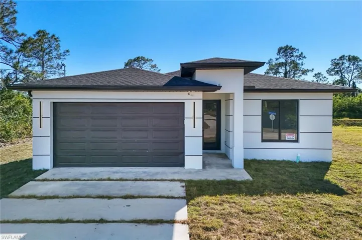 Prairie-style house featuring stucco siding, driveway, a front yard, and a garage