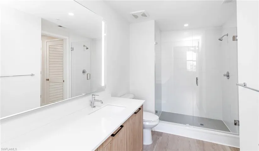 Full bath with a shower stall, recessed lighting, vanity, and toilet