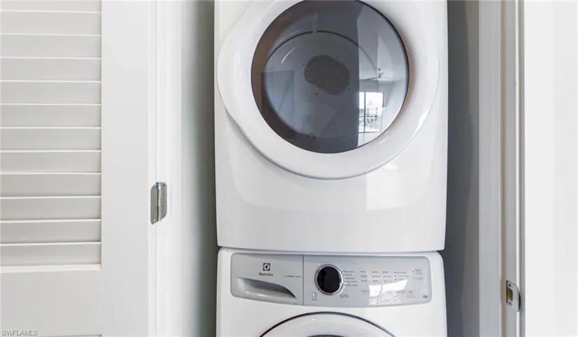 Clothes washing area featuring laundry area and stacked washer and dryer