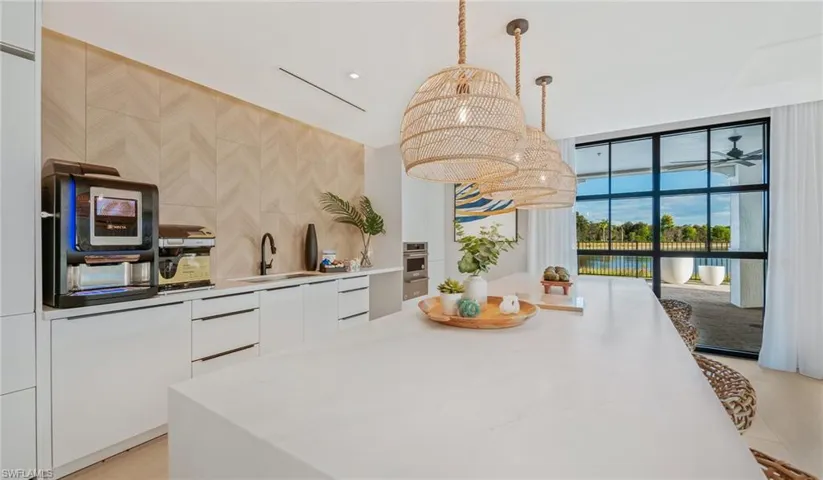 Kitchen featuring light countertops, white cabinetry, decorative light fixtures, modern cabinets, and a sink
