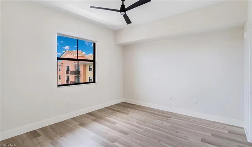 Empty room with baseboards, light wood-type flooring, and a ceiling fan