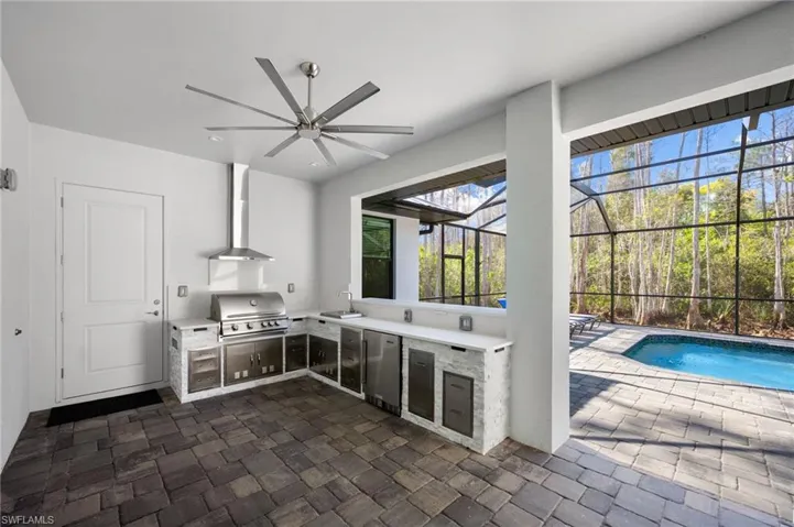 Expansive lanai, where a spacious pool and brand-new outdoor kitchen with built-in gas grill, beverage refrigerator, and sink create the perfect environment for entertaining and outdoor living.