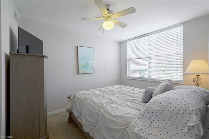 Carpeted bedroom featuring ceiling fan