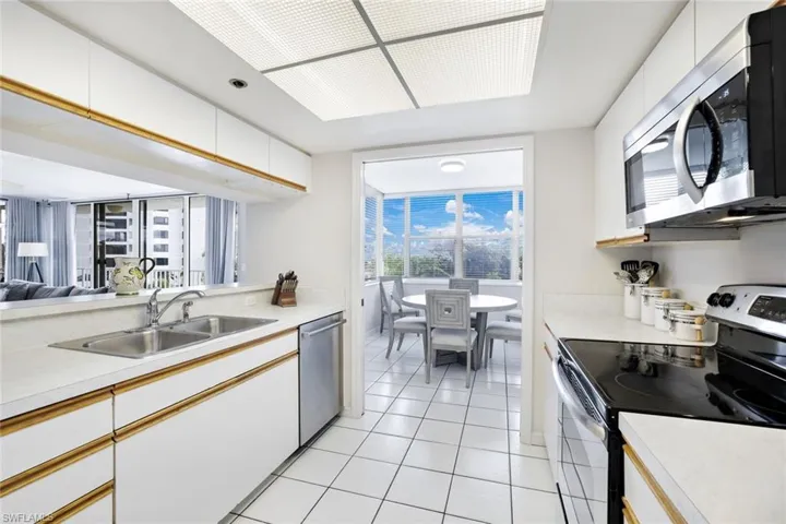 Kitchen with sink, stainless steel appliances, white cabinetry, and light tile floors