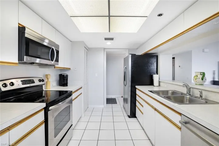 Kitchen featuring sink, light tile floors, white cabinetry, and appliances with stainless steel finishes