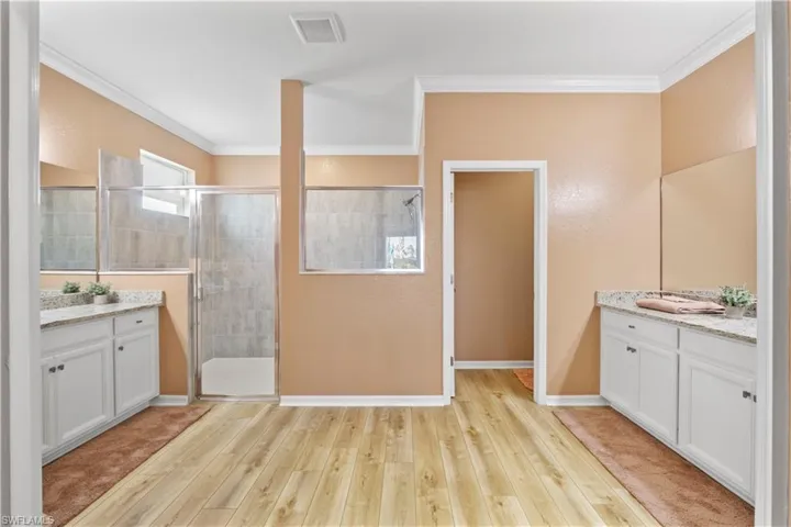 Bathroom featuring 2 vanities, oversized shower stall, crown molding