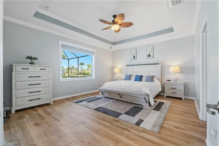 Primary suite w/tray ceiling, LVP flooring, ceiling fan. Sliding doors to Lanai.