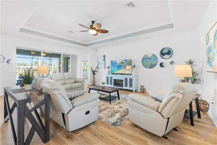Living area featuring a tray ceiling, ceiling fan. Furnished w/console fireplace