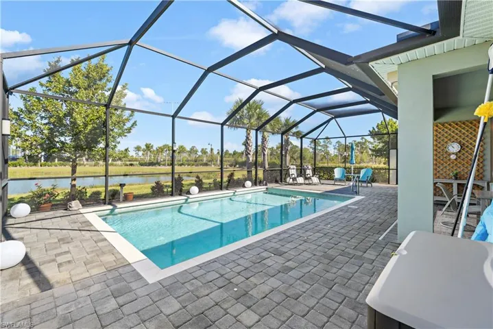 Heated pool with screened  enclosure, a water view, and a paved patio Lanai