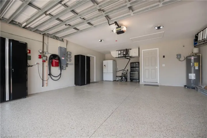 Garage with water heater, a garage door opener, and epoxy painted floors