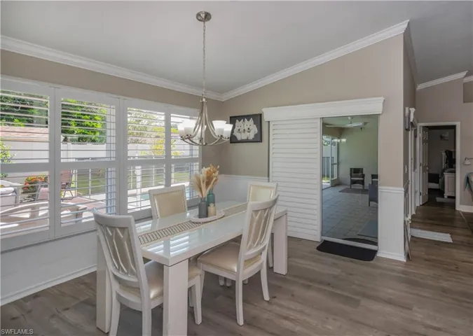 Dining room featuring a notable chandelier,  crown molding, plantation shutters, and plenty of natural light
