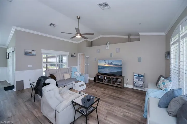 Living room featuring crown molding, ceiling fan, vaulted ceiling, and plantation shutters
