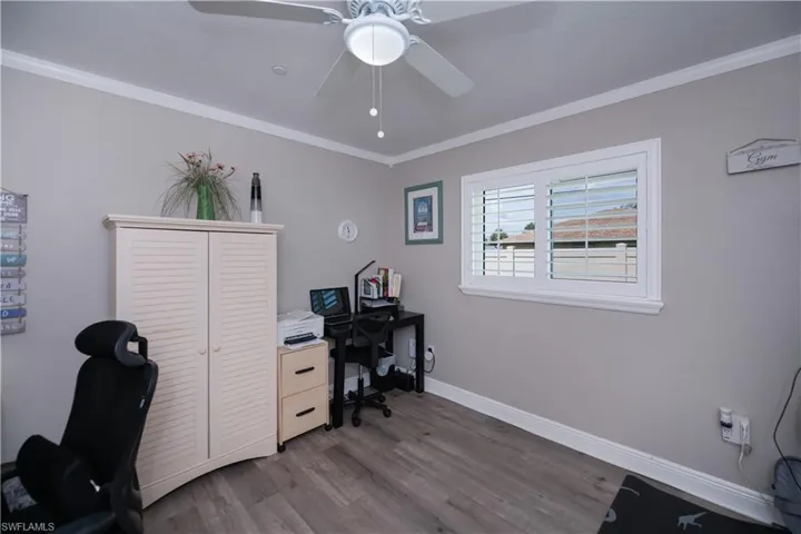 Guest bedroom featuring ornamental molding, ceiling fan, and LVT plank wood-style floors
