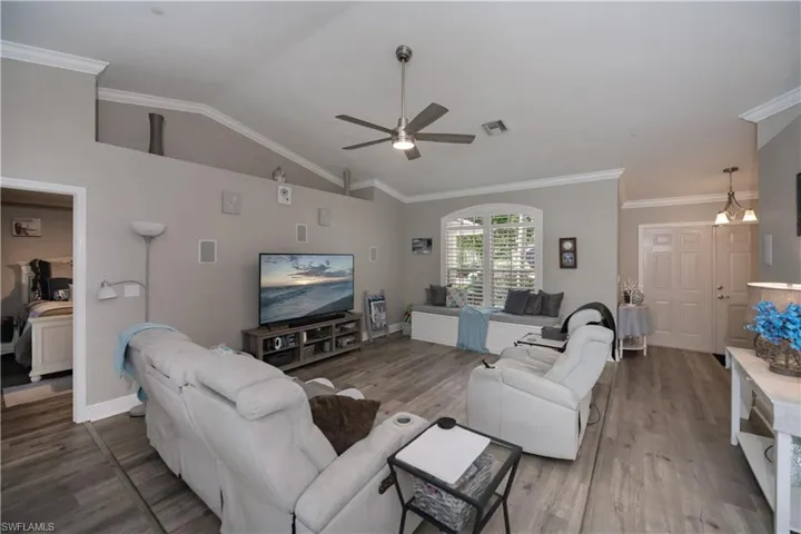 Living room with ceiling fan, ornamental molding, vaulted ceiling