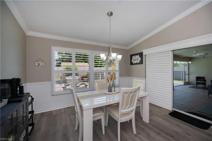 Dining room featuring  a notable chandelier, vaulted ceiling,  crown molding and plantation shutters