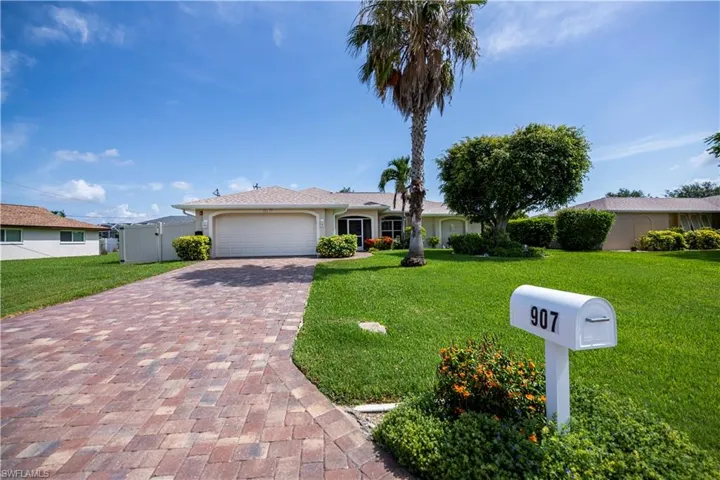 Ranch-style house with a garage and paver driveway