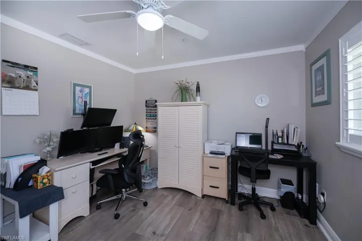 3rd bedroom currently used as an office featuring a healthy amount of sunlight, LVT wood-type flooring, ceiling fan, and crown molding