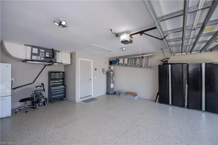 Garage with a garage door opener, electric water heater, and epoxy painted garage floor.