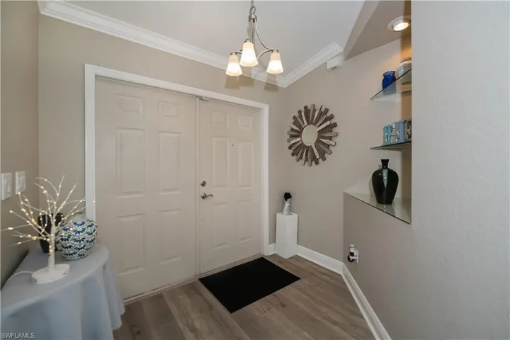 Foyer featuring an inviting chandelier, crown molding, and LVT plank flooring