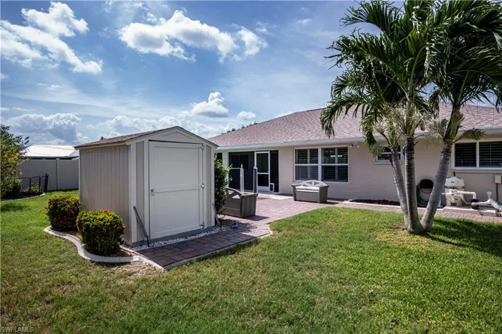 Back of house featuring a shed, a lawn, and a patio