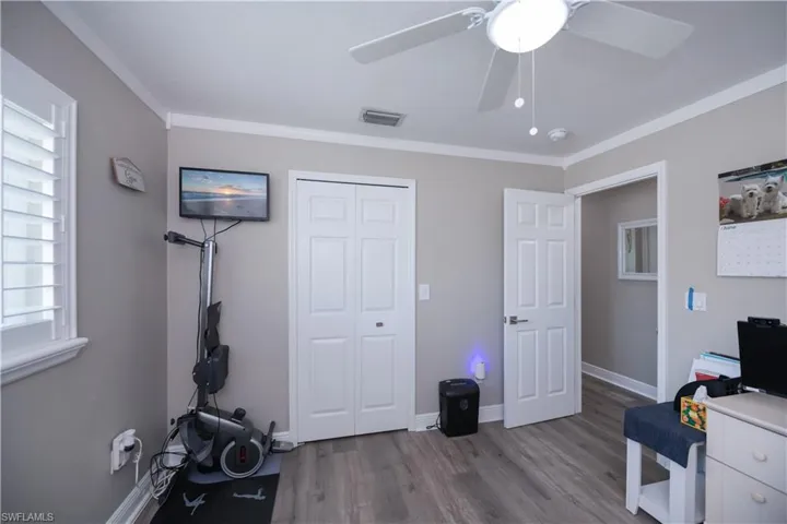 Guest bedroom with ornamental molding, ceiling fan, and LVT plank wood-style floors