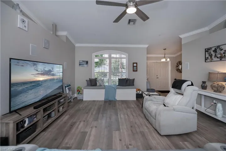 Living room with ceiling fan, crown molding, plantation shutters and LVT plank wood style flooring