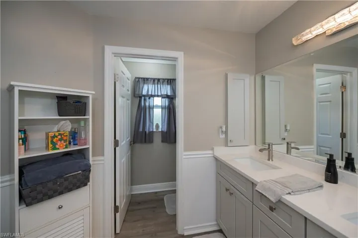 Bathroom with vanity with extensive cabinet space, water closet, and LVT plank wood-style floors