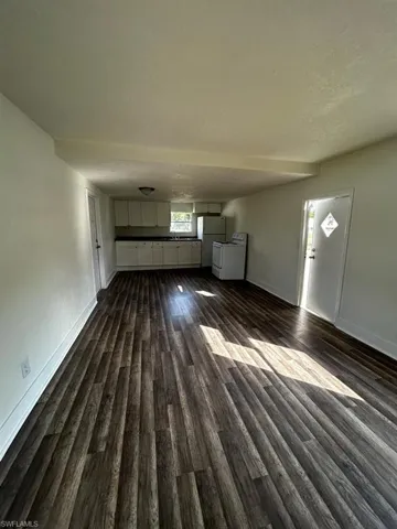 Unfurnished living room with dark wood-type flooring, sink, and a textured ceiling