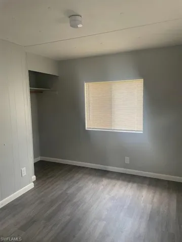 Unfurnished bedroom featuring dark hardwood / wood-style flooring and a closet
