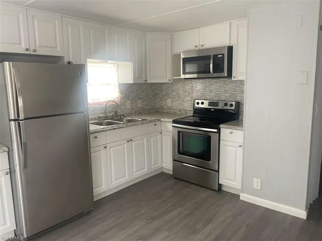 Kitchen featuring white cabinetry, stainless steel appliances, dark hardwood / wood-style floors, and sink
