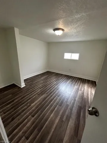Empty room featuring dark hardwood / wood-style floors and a textured ceiling