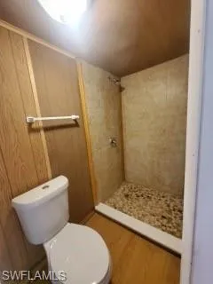 Bathroom featuring hardwood / wood-style flooring, a tile shower, and toilet