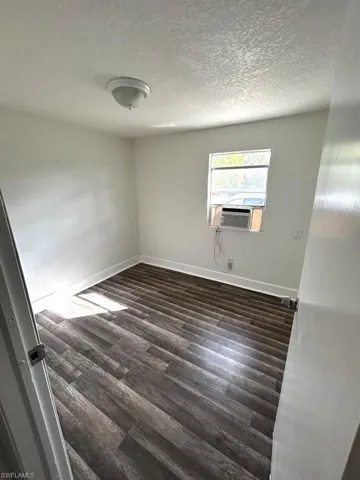 Spare room with cooling unit, dark hardwood / wood-style floors, and a textured ceiling
