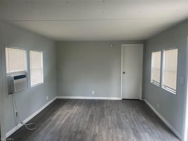 Empty room with cooling unit and dark hardwood / wood-style floors