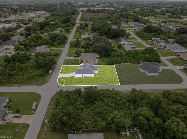 Corner lot property featuring a single-story residence, asphalt shingle roof, concrete driveway, and expansive parcel area