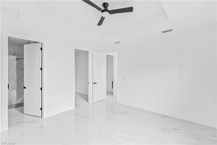 Tray ceiling with recessed lighting, large-format tile flooring, and matte black ceiling fan fixture with integrated lighting