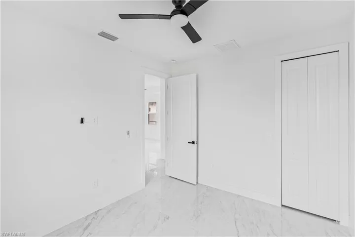 Interior space featuring stone-style flooring, a matte black ceiling fan, solid-core interior doors with matte black hardware, and a bi-fold closet