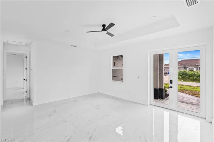 Interior featuring large-format tile flooring, a tray ceiling with a matte black ceiling fan, and full-glass paneled exterior doors