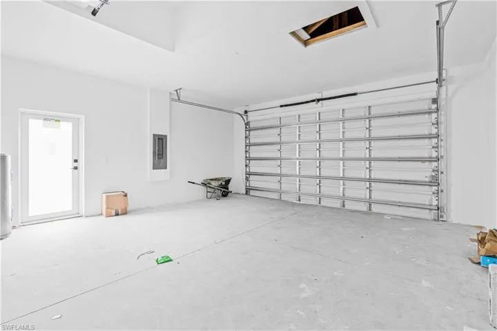 Attached garage featuring an automated overhead door, concrete flooring, high ceilings, and a dedicated exterior access door