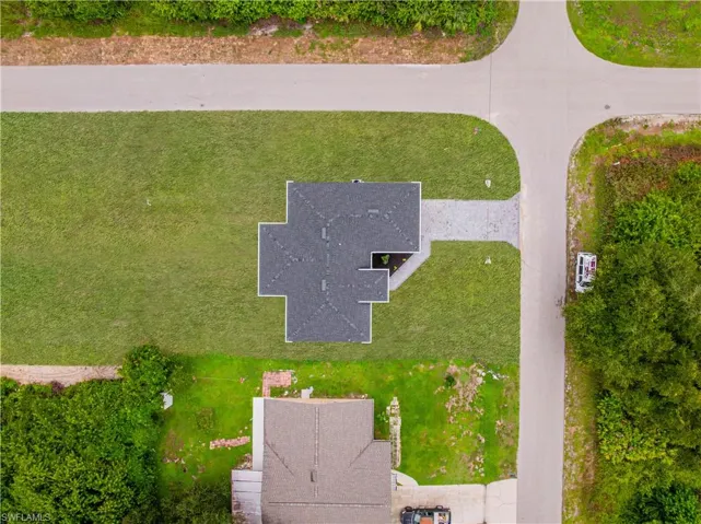 Corner lot with an expansive yard, shingled roofline, and paved driveway