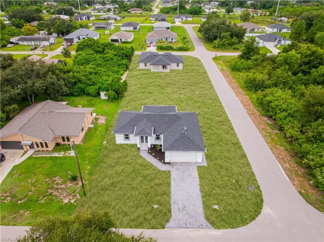 Single-story residence featuring a multi-gable roofline, attached two-car garage, gray stone-composite driveway, and expansive corner lot