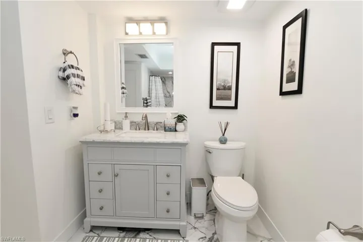 Bathroom featuring vanity, light marble finish floors, and a shower with curtain