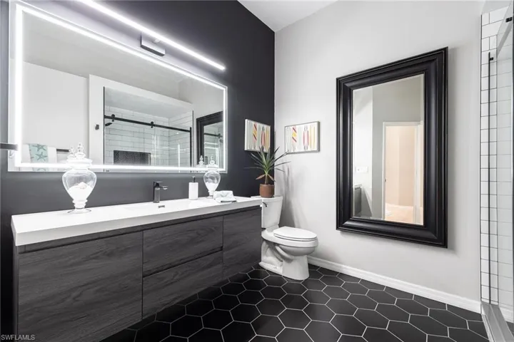 This is gorgeous renovated bathroom. Floating vanity, tiled flooring, electric light, contemporary style.